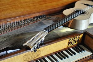 Gitarre liegt auf einem offenen Klavierflügel. 