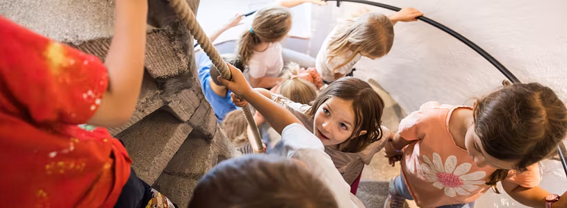 Mehrere Kinder steigen im Schloss Lenzburg eine Wendeltreppe hoch.