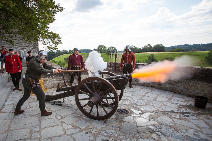 Mittelalterlich gekleidete Männer schiessen mit einer Kanone auf Schloss Lenzburg