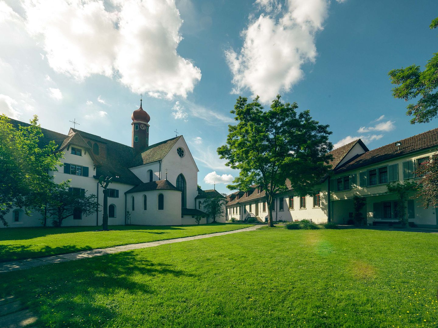 Aussenaufnahme Kloster Wettingen mit blauen Himmel und einer grünen Wiese im Vordergrund.
