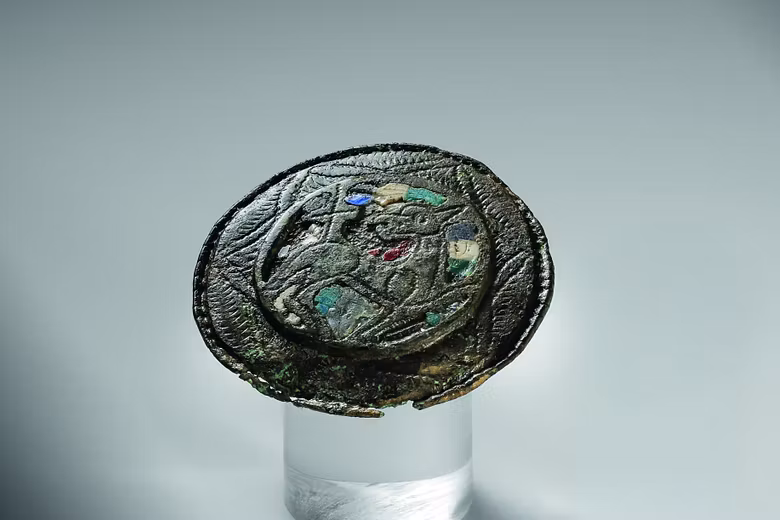 Scheibenfibel aus Buntmetall mit farbigen Emaille-Einlagen. Eingraviert ist das Lamm Gottes – ein Sinnbild für die Auferstehung Christi.