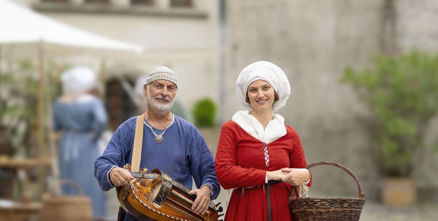 Eine mittelalterlich gekleidete Frau und ein Musiker, ebenfalls in Mittelalter-Kleidung.