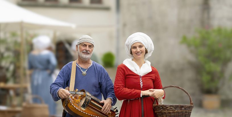 Eine mittelalterlich gekleidete Frau und ein Musiker, ebenfalls in Mittelalter-Kleidung.