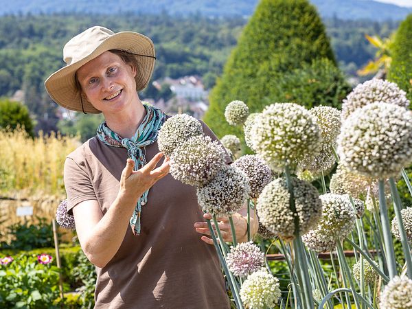 Eine Gärtnerin präsentiert eine Pflanze im Garten von Schloss Wildegg.