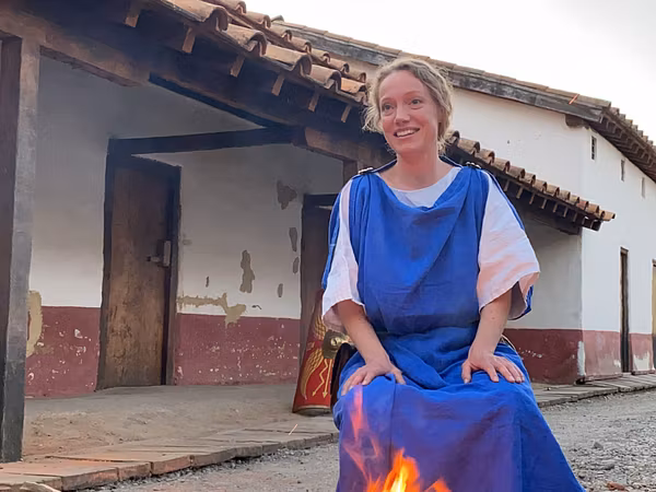 Eine römisch gekleidete Frau steht in der Gasse vor der Mannschaftsunterkunft im Legionärspfad Vindonissa.