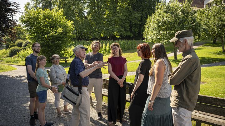 Besucherinnen und Besucher mit einem Museumsführer stehen im Park der Klostesrhalbinsel Wettingen
