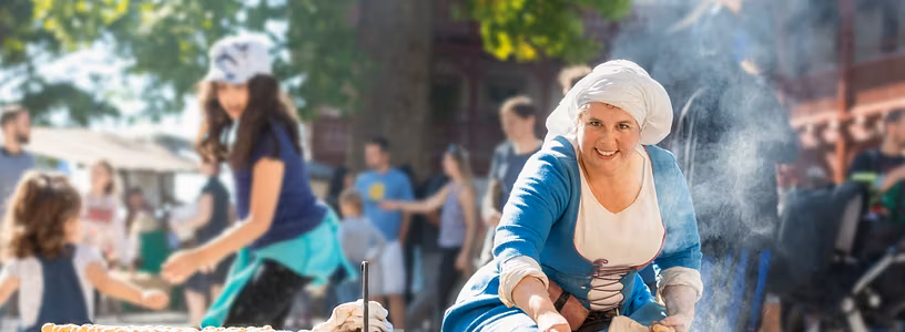 Eine mittelalterliche gekleidete Frau kocht am Mittelaltermarkt von Schloss Lenzburg.
