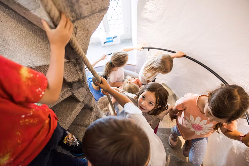 Mehrere Kinder gehen die Wendeltreppe im Schloss Lenzburg hoch (Aufnahme von oben)