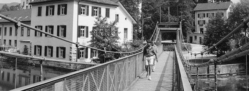 Schwarz-weiss-Aufnahme Spinnerei Wettingen mit Brücke im Vordergrund.