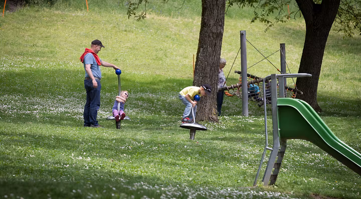 Eine Frau und mehrere Kinder auf der Wiese im Spielplatz von Schloss Wildegg