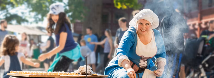 Eine mittelalterliche gekleidete Frau kocht am Mittelaltermarkt von Schloss Lenzburg.