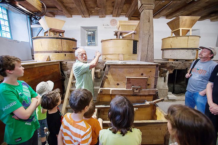 Ein Museumsführer mit einer Gästegruppe in der Mühle von Schloss Hallwyl.