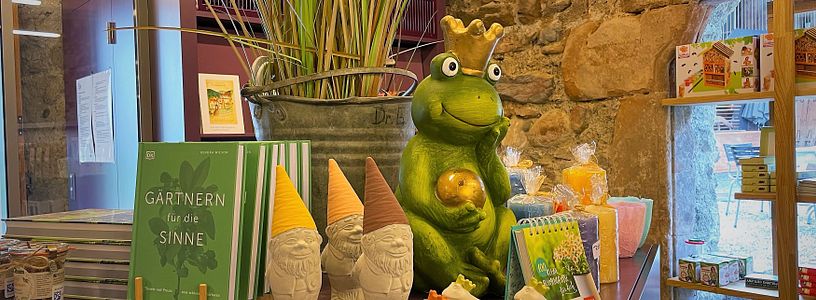 Blick in den Museumsshop Schloss Hallwyl: Ein grosser Frosch mit Gartenzwergen für den Garten, daneben weitere Artikel für den Garten
