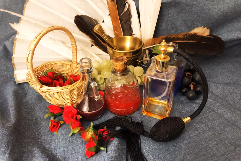 Korb mit Rosenblüten, Parfümflakon, Mörser und einem Fächer