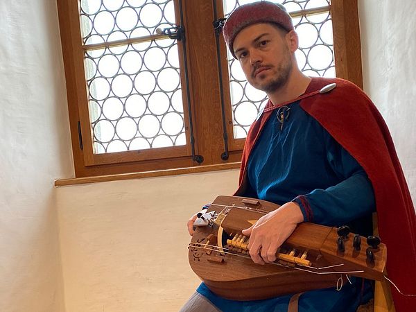 Eine als mittelalterlicher Spielmann verkleidete Person mit einer Drehleiher auf Schloss Lenzburg.