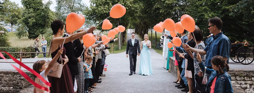 Ein Hochzeitspaar schreitet durch eine Festgesellschaft, die vor Schloss Hallwyl Spalier steht.