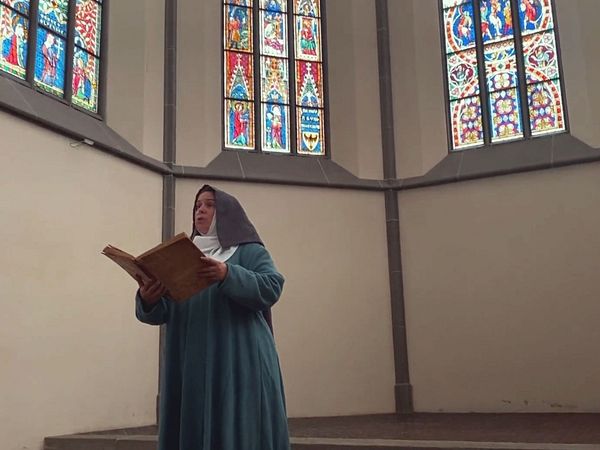 Eine als Udelhild von Hallwyl gekleidete Person steht im Kloster Königsfelden und hält ein grosses Buch in den Händen.