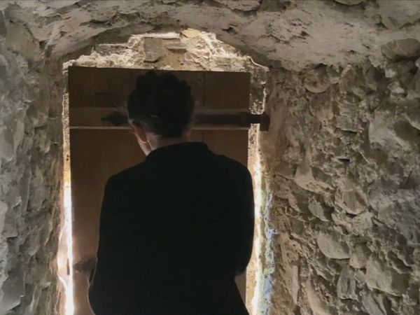 Eine Person steht in einem wenig belichteten Gang auf Schloss Hallwyl.
