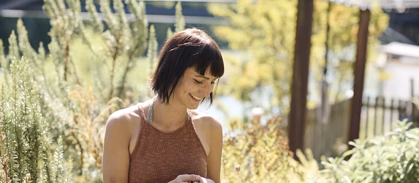 Eine Frau mit Korb in einem Garten. Sie lächelt.