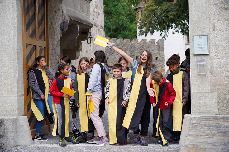Schülerinnen und Schüler in Kostümen stehen lachen i Schlosstor von Schloss Hallwyl