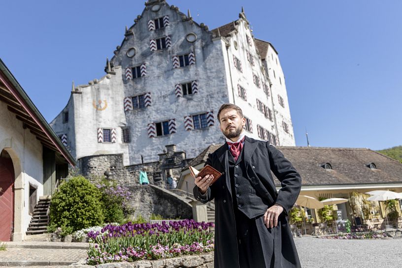 Ein Mann im historischen Kostüm steht vor Schloss Wildegg