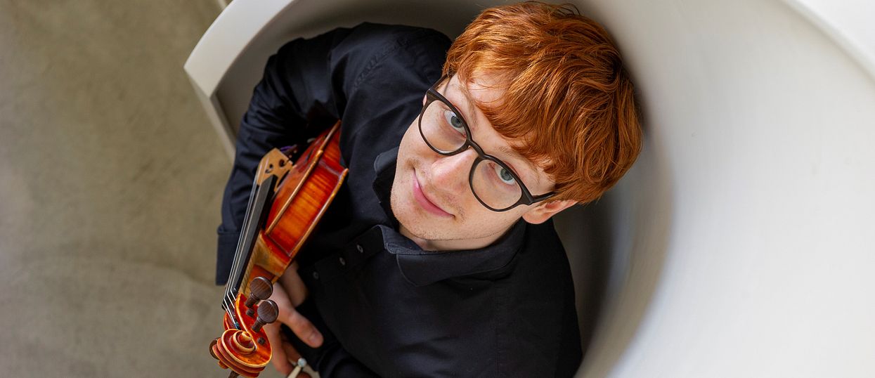 Musiker Silvan Dezini hält eine Geige in der Hand.
