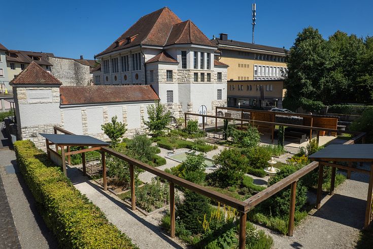 Römischer Garten Vindonissa Museum: Übersicht des Gartens mit geometrisch angelegten Wegen und Gartenbeeten. Im Hintergrund das Museumsgebäude vom Vindonissa Museum.