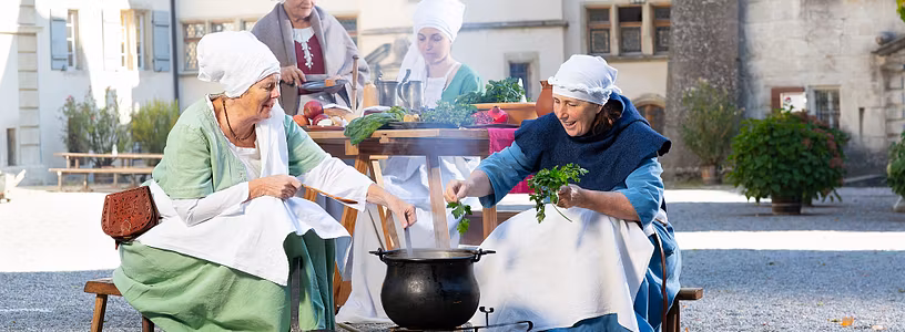 Vier Frauen in historischen Kostümen kochen im Hof von Schloss Lenzburg
