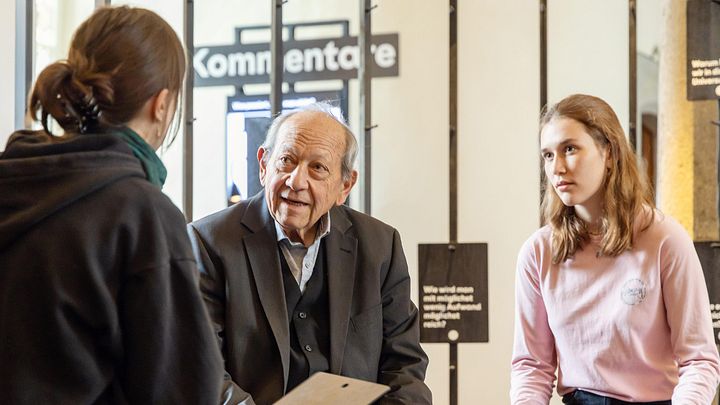 Ein älterer Mann im Gespräch mit zwei jugendlichen Frauen.