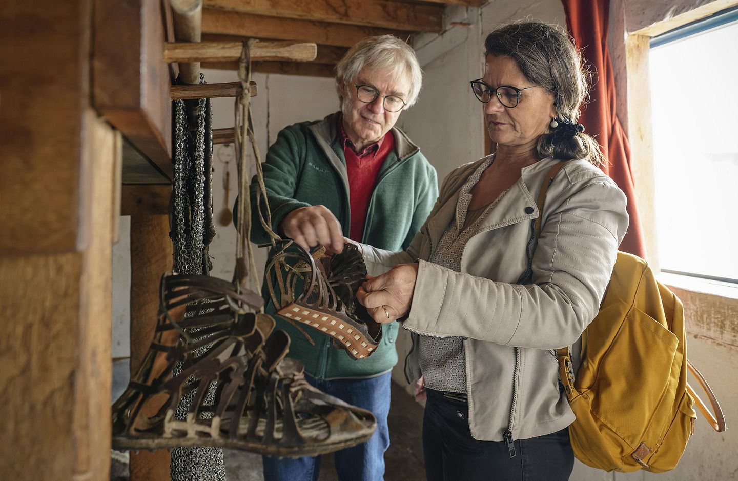 Ein Mann und eine Frau stehen in einer römischen Legionärsunterkunft. Sie betrachten römische Sandalen.