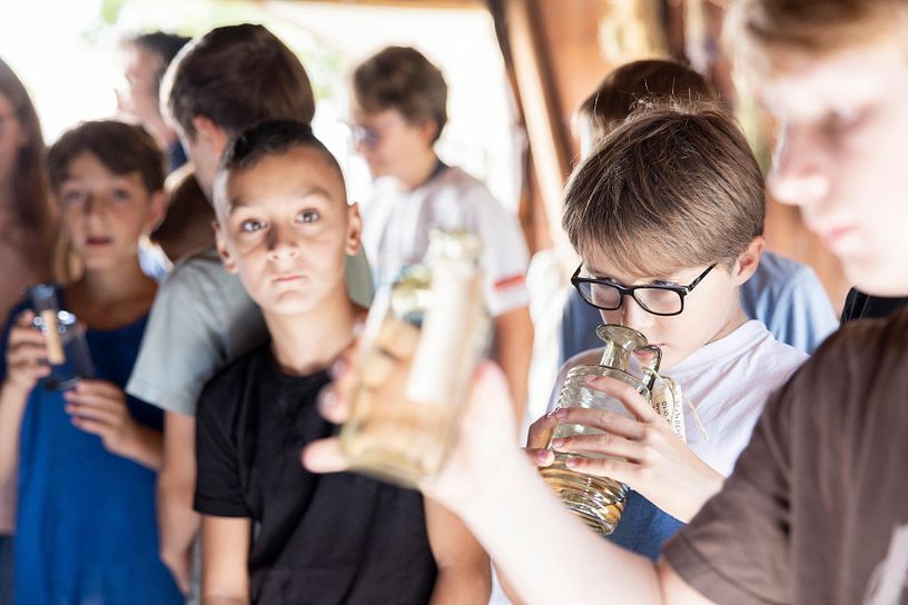 Mehrere Kinder stehen im Feldlazarett des Legionärspfad Vindonissa und riechen an unterschiedlichen Glasgefässen 