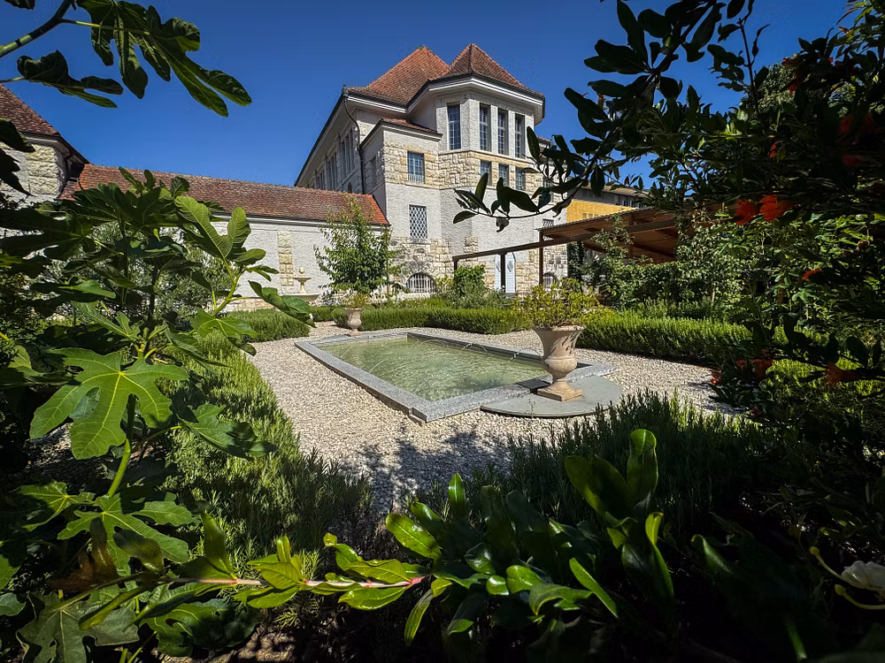 Römischer Garten Vindonissa Museum: Übersicht des Gartens mit geometrisch angelegten Wegen und Gartenbeeten. Im Hintergrund das Museumsgebäude vom Vindonissa Museum.