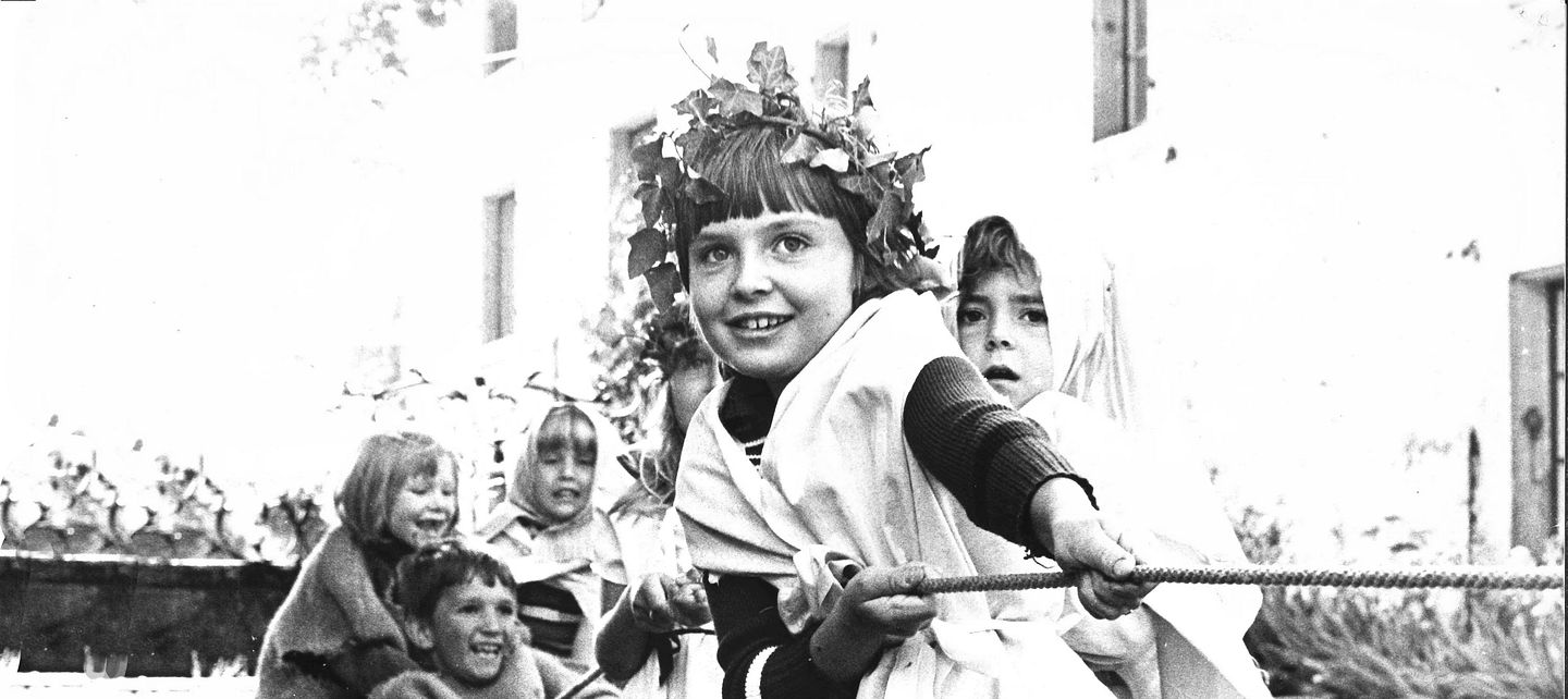 Historische Aufnahme in schwarz-weiss: Geschichtsvermittlung auf Schloss Lenzburg. Kinder in Kostümen beim Seilziehen im Schlosshof