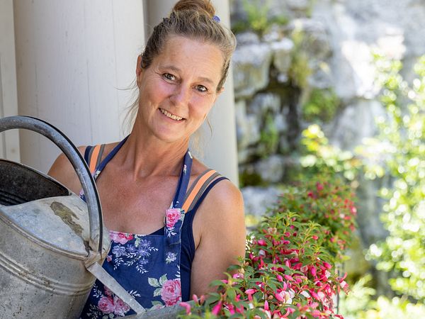 Eine Frau giesst Blumen mit einer Giesskanne im Garten von Schloss Wildegg.