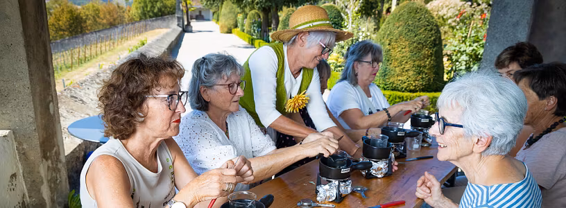 Workshop im Garten: Eine Gruppe Frauen setzt am Tisch und kocht Salbe; im Hintergrund der Garten von Schloss Wildegg