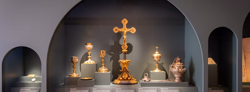 Ausstellung in der Mönchskirche Kloster Wettingen: Verschiedene Objekte in einer Vitrine, u.a. ein grosses Altarkreuz