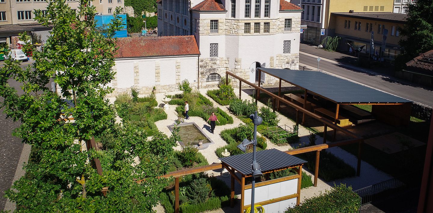 Römischer Garten Vindonissa Museum: Übersicht des Gartens mit geometrisch angelegten Wegen und Gartenbeeten. Im Hintergrund das Museumsgebäude vom Vindonissa Museum.