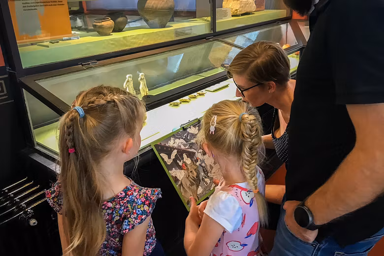 Eine Familie steht mit einem Plan vor einer Vitrine im Vindonissa Museum.
