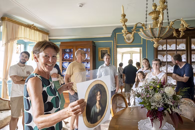 Eine Museumsführerin mit einer Gruppe Besucherinnen und Besucher in einem historischen Raum von Schloss Wildegg. Die Frau blickt direkt lachend in die Kamera.