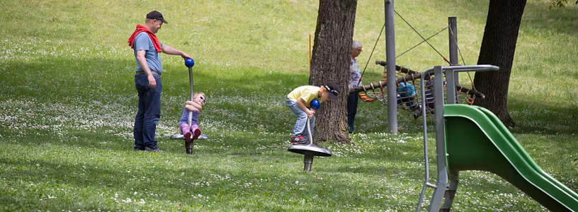 Eine Frau und mehrere Kinder auf der Wiese im Spielplatz von Schloss Wildegg