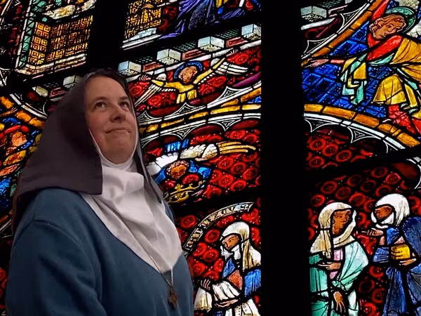Eine Frau im Nonnengewand vor einem Glasfenster im Kloster Königsfelden