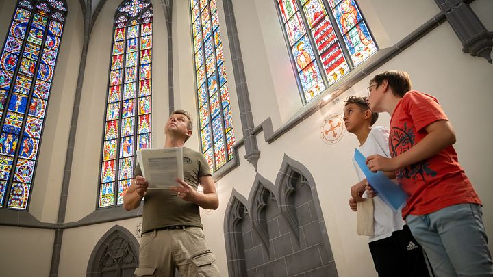 Besucher und Besucherinnen betrachten die berühmten Glasfenstern auf Kloster Königsfelden