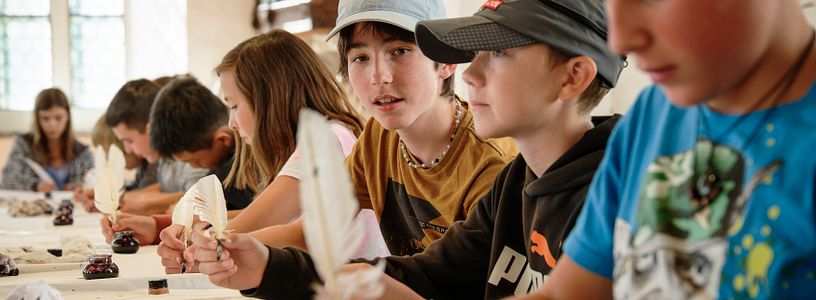 Eine Schulklasse beim Schreiben mit Tinte und Federkiel.