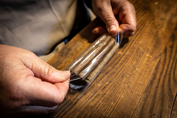 Ein Bündel gerollte Zigarren wird in Plastikfolie verpackt.