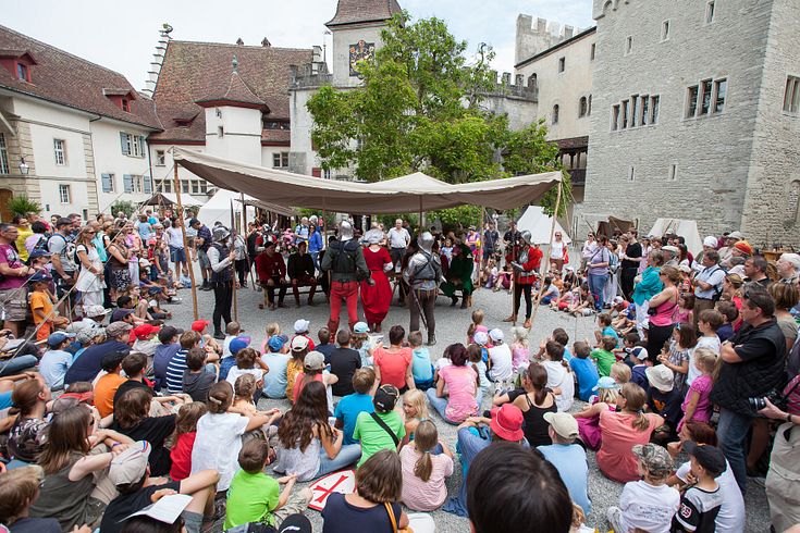 Belebter Hof von Schloss Lenzburg, in der Mitte steht ein grosses Zelt mit mittelalterlich gekleideten Personen.