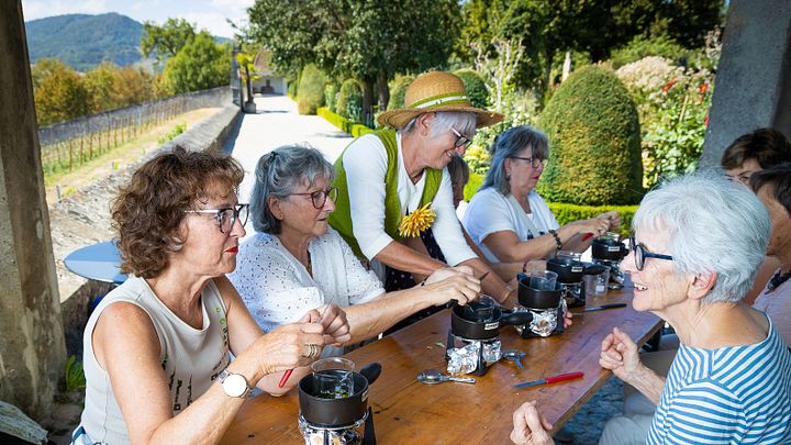 Workshop im Garten: Eine Gruppe Frauen setzt am Tisch und kocht Salbe; im Hintergrund der Garten von Schloss Wildegg