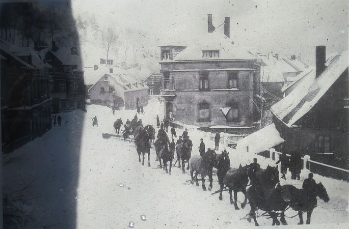 Schönheide im Erzgebirge: Schneepflug von Pferden gezogen, Quelle: Wikimedia. Schwarzweiss Foto. Winterimpression von Schönheide. 10 Pferden ziehen einen Schneepflug auf der Strasse.