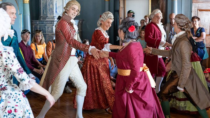 Eine Gruppe in barocken Kostümen tanz im Salon von Schloss Wildegg.