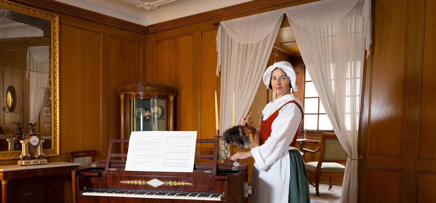 Dienstmagd staubt Kerzenständer im Salon von Schloss Hallwyl ab