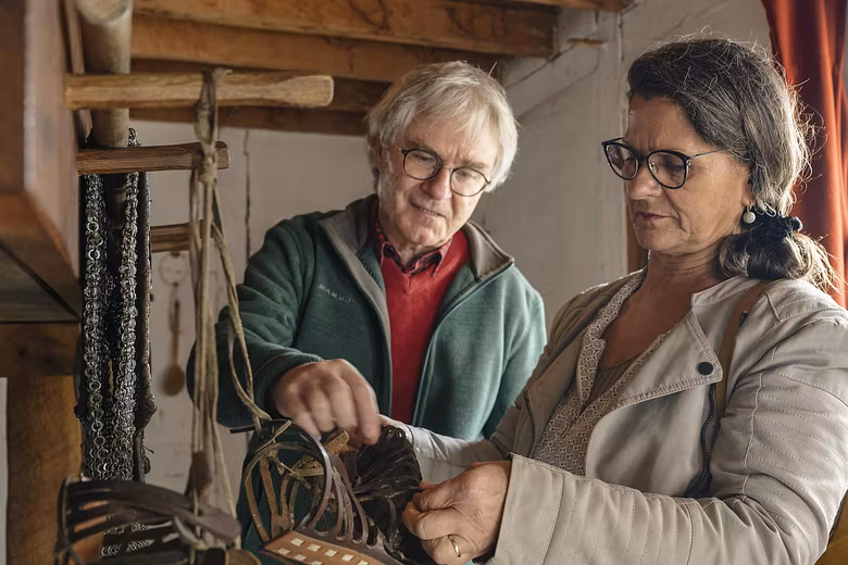 Ein Mann und eine Frau stehen in einer römischen Legionärsunterkunft. Sie betrachten römische Sandalen.